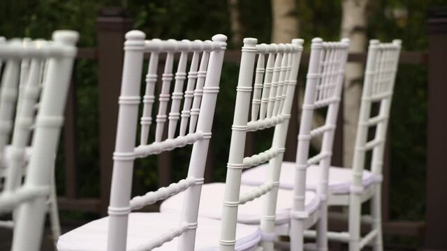 White plastic Chiavari chairs in rows. Outdoor wedding ceremony.