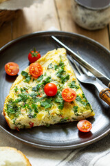 Breakfast of omelet with vegetables, herbs and cheese, served with bread and coffee.