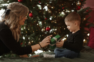 Young beautiful woman posing with her cute little son in with festive lights in the background on Christmastime