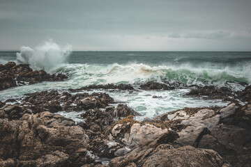 Waves crashing the rocks on a dark beach