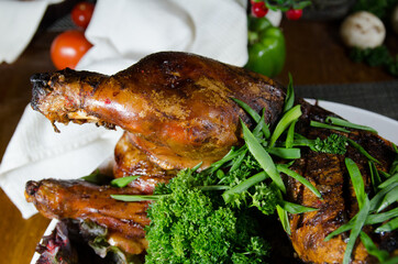a whole baked pig stuffed with buckwheat decorated with greens on a large round white plate on a wooden table. A large festive table, a dish. Russian cuisine Russian traditions