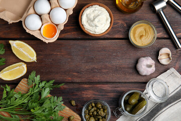 Fototapeta na wymiar Tasty tartar sauce and ingredients on wooden table, flat lay. Space for text