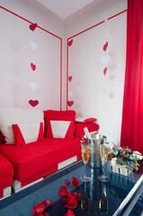 red and white romantic room interior with hearts on the wall champagne on the table