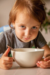 Child and baby food concept. Little child girl sits on a high chair and eats fruits breakfast.