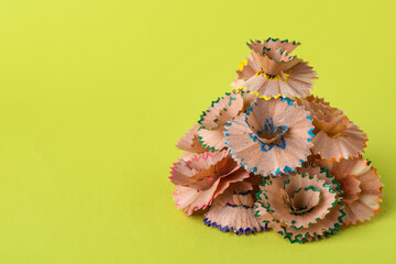 Pile of colorful pencil shavings on light green background. Space for text