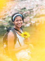 Beautiful brown skinned girl holding a sun flower hiking