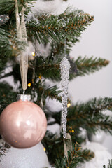 Christmas decorated tree in soft pink colors against the background of white classic fireplace with Christmas decorations. Details of New Year festive living room interior