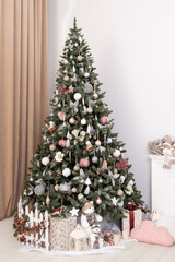 Decorated fir tree and gift boxes near fireplace in living room