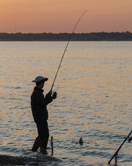 Rear view of Asian man bank fishing catch catfish on the hook at Lavon Lake near Dallas, Texas, USA