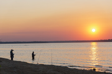 Naklejka na ściany i meble Two Asian men with boot and hat fishing at sunrise on Lavon Lake near Dallas, Texas, USA