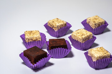 Various chocolate pralines candies in purple molds highlighted on a white background. Top view. The concept of goodies, delicious photography