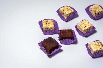 Various chocolate pralines candies in purple molds highlighted on a white background. Top view. The concept of goodies, delicious photography