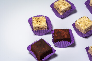 Various chocolate pralines candies in purple molds highlighted on a white background. Top view. The concept of goodies, delicious photography