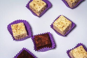 Various chocolate pralines candies in purple molds highlighted on a white background. Top view. The concept of goodies, delicious photography