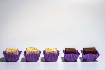 chocolate brown cupcakes with white icing in purple form in one line on a light background, close up. The concept of delicious and healthy sweet 