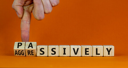 Passively or aggressively symbol. Businessman turns cubes and changes the word passively to aggressively. Psychological and passively or aggressively concept. Beautiful orange background, copy space.