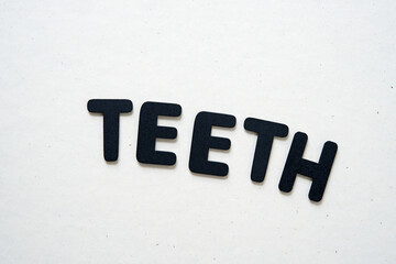 the word "teeth" written in black chalk letters on a light background