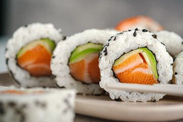 A set of fresh sushi rolls with salmon, avocado and black sesame seeds close up. California roll, selective focus