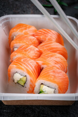 Classic Philadelphia roll set with cream cheese, cucumber and salmon in a delivery box. Japanese dish with raw salmon