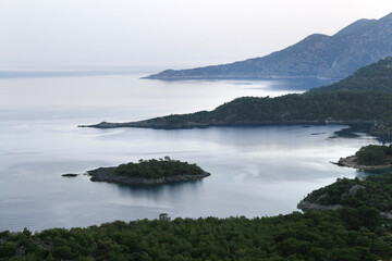 Fototapeta na wymiar calm blue sea with an island and peninsula in the evening