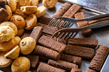 Fresh pastries, delicious shortbread cookies on a tray with metal tweezers for gripping.