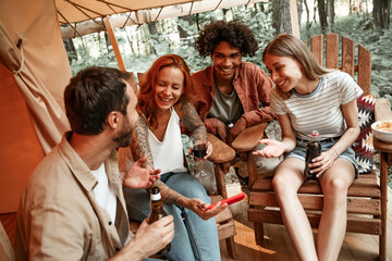 Happy group of young people drinking wine beer using phones social media during picnic in forest smiling millennial users customers talking shopping online sit at table, mobile tech lifestyle concept