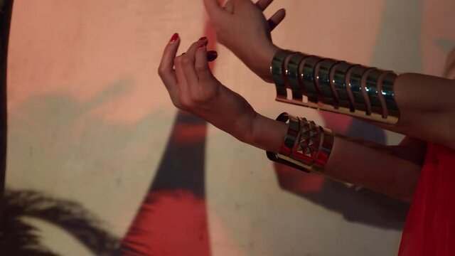 woman hands with red manicure and golden bracelets, moving sexually, exotic oriental dance show