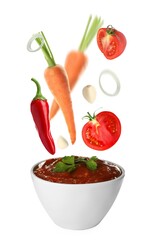 Different ingredients falling into ceramic bowl with delicious adjika sauce on white background