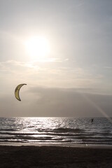 Paracaídas y hombre moviéndose por la brisa del mar en atardecer en la playa.