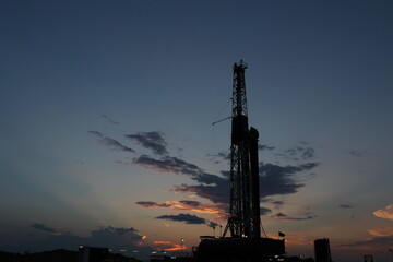 Drilling rig towering over the West Texas landscape at dusk, excellent screensaver or desktop photo.