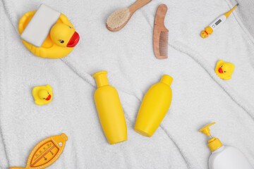 Baby bath products flat lay. Children cosmetics set: rubber duck, comb, thermometer on a white towel. Copy space for text