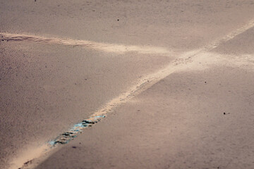 Fototapeta na wymiar A groove in the asphalt forming a crosshair. Remains of water on the asphalt after rain.