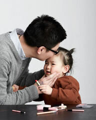 Asian little girl and parents playing makeup game, indoor white background
