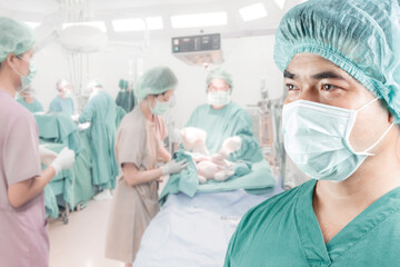 mature male surgeon with baby and team surgeon in operating room