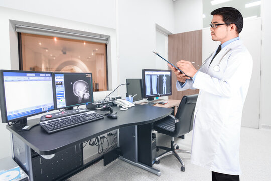 doctor writing clipboard for diagnosis at magnetic resonance (MRI) on screen in operation room