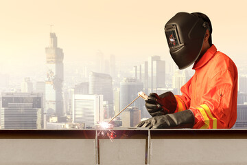 Industrial welder welding steel structure construction by metal arc welding at high building construction against urban scene.