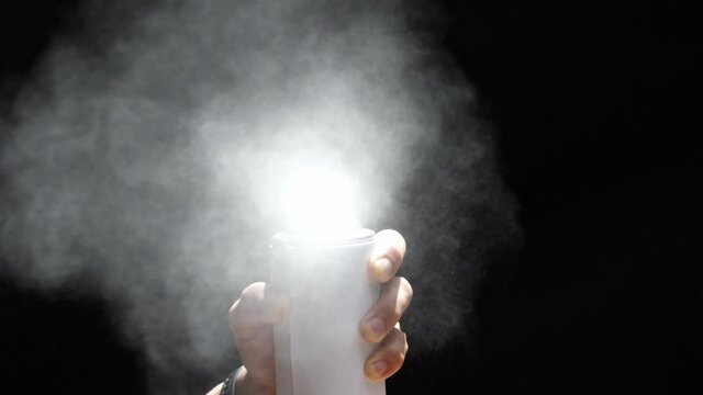 Slow motion speed closeup scene in front view of aerosol can when spraying, white color spray isolated on black background, damage ozone made green house effect problem cause of  global warming.