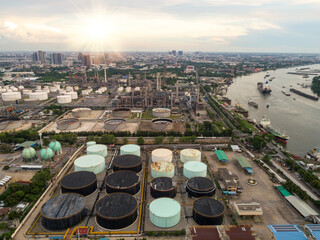 Aerial view above oil refinery petrochemical industrial plant in sunrise against urban scene