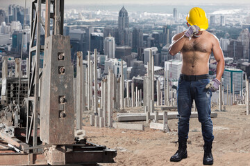  Brawny worker at pile driver works to set precast concrete piles in a construction site against city