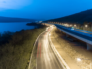 Tail lights of the cars during driving on highway and overpass in sunset