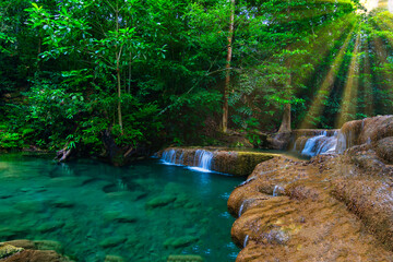 Erawan waterfall in the tropical jungle surrounded by a natural with turquoise clear fresh water and green forest on mountain in kanchanaburi, thailand.