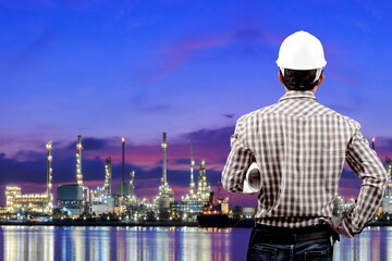 Fototapeta na wymiar Engineer holding blueprint working at oil refinery petrochemical industrial plant at twilight