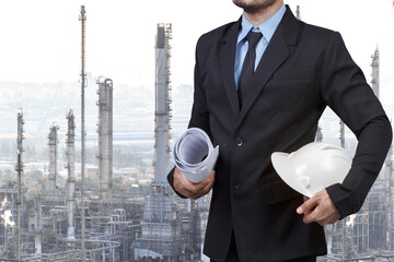 Engineer holding hard hat and blueprint  for working at oil refinery petrochemical industrial plant