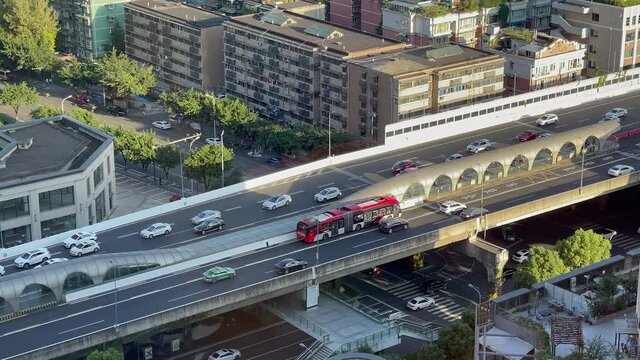 Time-lapse of inner city traffic in Chengdu on and beneath overpass flyover where there is the Chengdu Bus Rapid Transit System (BRT) station as buses stop and take passengers then go