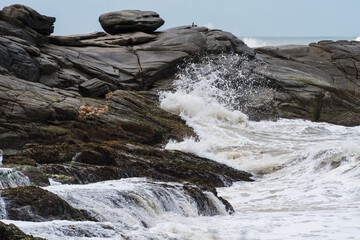 Strong waves crashing on the rocks of Rio das Ostras beach in Rio de Janeiro.