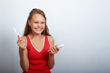 a beautiful girl of 11 years old brushes her teeth on a white background