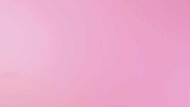 Close-up of a man's hand pointing to the left side, showing a thumb sign isolated on a pink studio background. High quality 4k footage