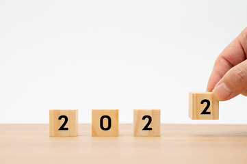 A man holding a wooden cube with 2022 numbers in the white background