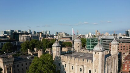 Panorama curve footage of top of White Tower and surrounding buildings. Historic medieval part of Tower of London. Union jack waving in wind. London, UK