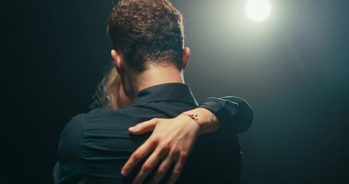 Experienced trainer with many years of experience spends time in dark studio, teaches new partner ballroom dancing explains figures they choreograph get along together dynamic change of moves